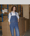 A.P.C. Black Friday - a woman in overalls standing in a warehouse setting