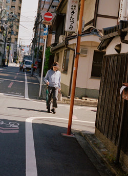 Old man wearing hat walking down Japanese street
