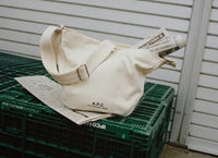 Beige bag with a strap on a green crate against a white wall
