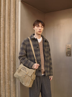 A.P.C. The Brand - Man wearing plaid wool jacket and grey pants standing in front of door entrance.a