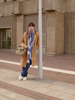 A.P.C. The Brand - Man wearing long coat and scarf leaning on pole in front of university.