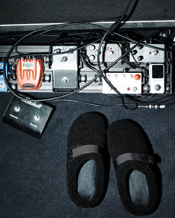 A.P.C. x Subu - Black Subu sandal next to guitar accessories.