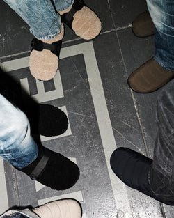 A.P.C. x Subu - 5 people standing in a circle all wearing different Subu sandals.
