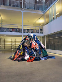 A.P.C. Recycling - a big pile of clothing in the middle of an office