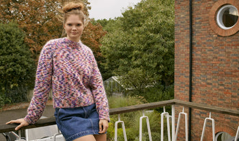 A.P.C. Women Sale Skirts, Shorts - Woman standing on bridge wearing coat and jeans.