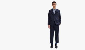 A.P.C. Men's Suits & Blazers - Man leaning on kitchen counter wearing white corduroy shirt and brown pants.
