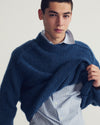 Man sitting in A.P.C. apparel with light backdrop, revealing his undershirt