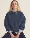 Woman sitting in A.P.C. apparel with light backdrop