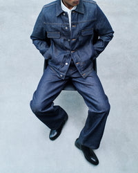 A.P.C. Raw Selvedge Indigo Denim Journal Entry - Man wearing denim jacket and jeans sitting on chair.