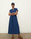 female model standing, wearing denim cap, denim dress, leather sandals