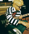 A.P.C. Brain Dead - a seated man holding a guitar in a music studio