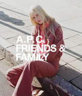 A.P.C. Women All - Woman wearing pink denim jacket and jeans sitting on curb.