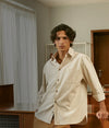 Male model wearing a strippy shirt, leaning on a piece of furniture.