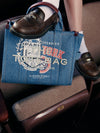 Closeup of a A.P.C. Marc Jacobs tote bag with a foot on it